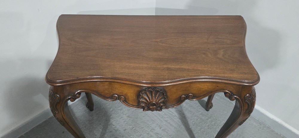 A dark mahogany console table featuring a shaped serpentine top, a central shell carving on the apron, and four cabriole legs. View IX