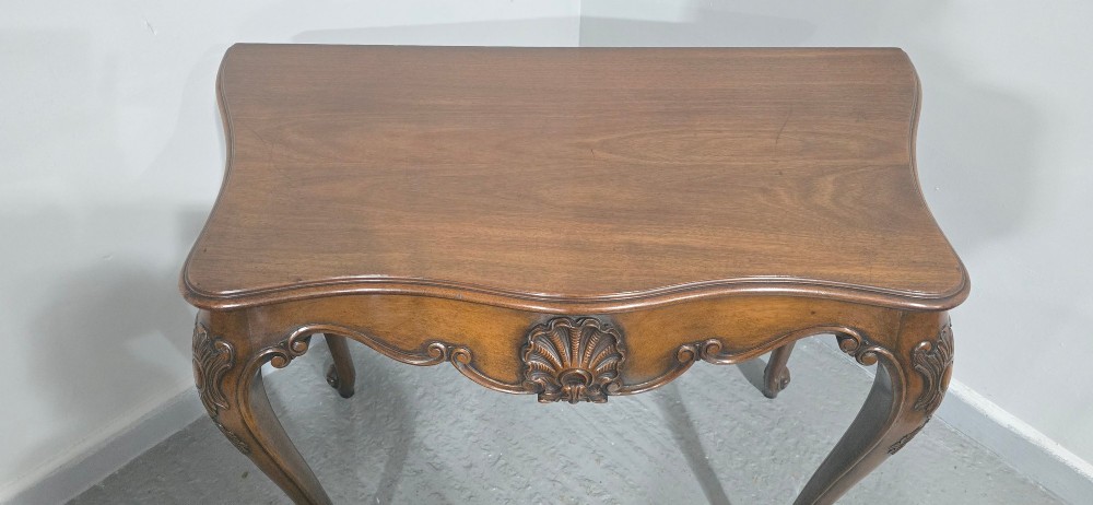 A dark mahogany console table featuring a shaped serpentine top, a central shell carving on the apron, and four cabriole legs. View X