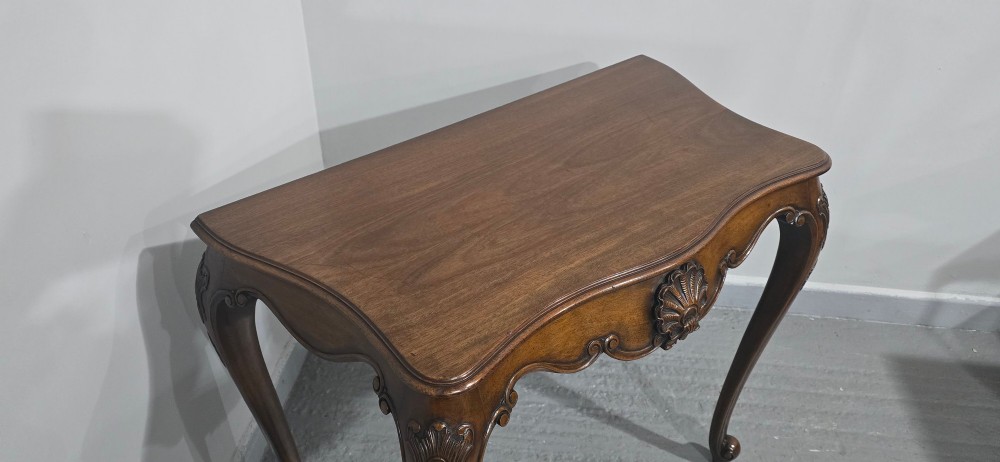 A dark mahogany console table featuring a shaped serpentine top, a central shell carving on the apron, and four cabriole legs. View XI