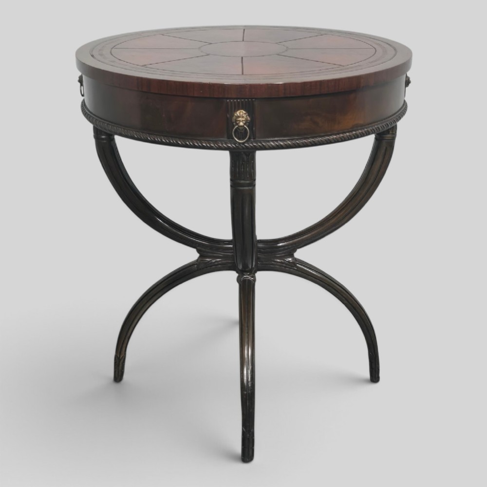 A circular mahogany occasional centre table with a segmented veneered top, brass lion mask handle, and curved reeded legs.