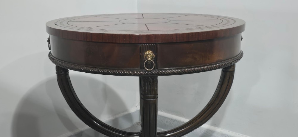 A circular mahogany occasional centre table with a segmented veneered top, brass lion mask handle, and curved reeded legs. View VI