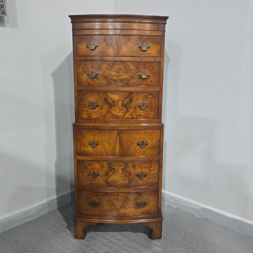 A small bowfront burr walnut chest on chest featuring stacked drawers with brass handles and bracket feet. View II