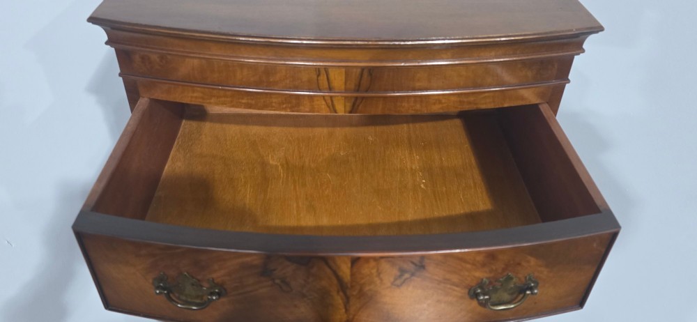 A small bowfront burr walnut chest on chest featuring stacked drawers with brass handles and bracket feet. View VI