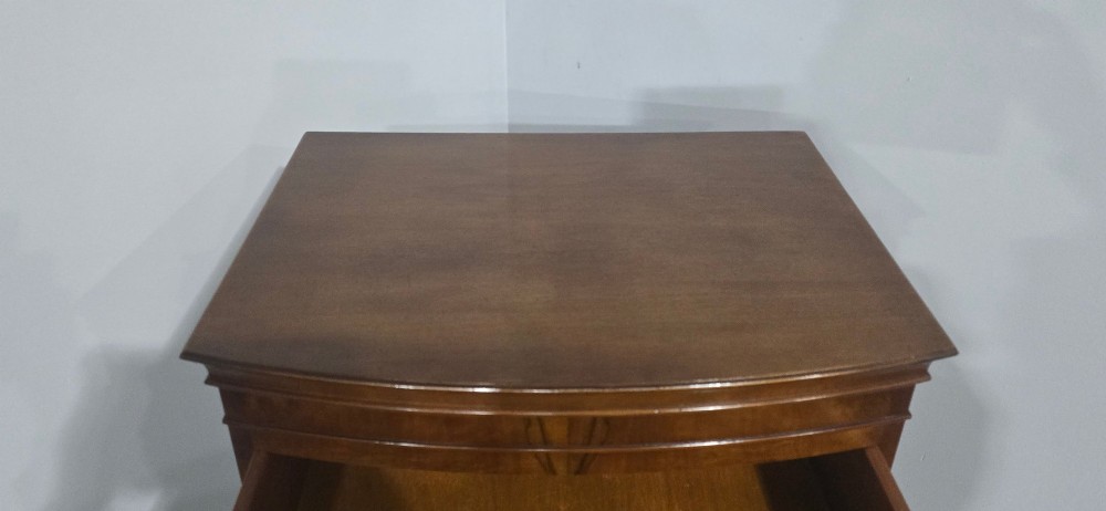A small bowfront burr walnut chest on chest featuring stacked drawers with brass handles and bracket feet. View VII