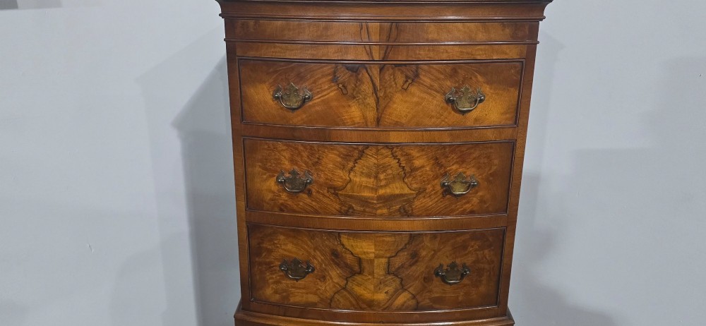 A small bowfront burr walnut chest on chest featuring stacked drawers with brass handles and bracket feet. View VIII