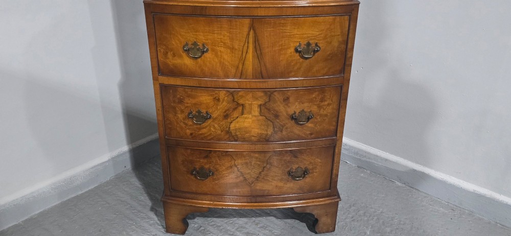 A small bowfront burr walnut chest on chest featuring stacked drawers with brass handles and bracket feet. View IX