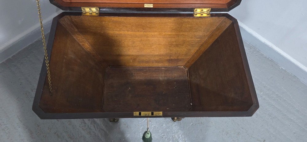 A tapered sarcophagus-shaped dark mahogany wine cooler featuring satinwood line inlay, brass lion paw feet, and a central keyhole with a green tassel. View VII