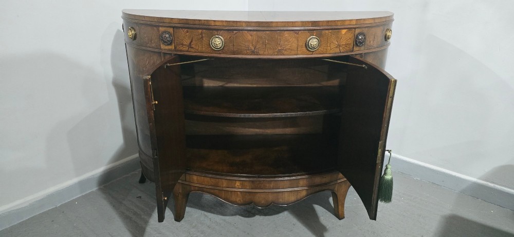 A semi-circular burr yew wood side cabinet featuring brass mounts along the frieze and central double doors. View XII