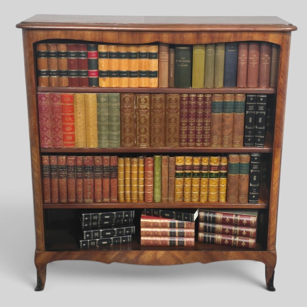 An open-fronted French walnut bookcase featuring adjustable internal shelves, a shaped apron, and short cabriole legs.