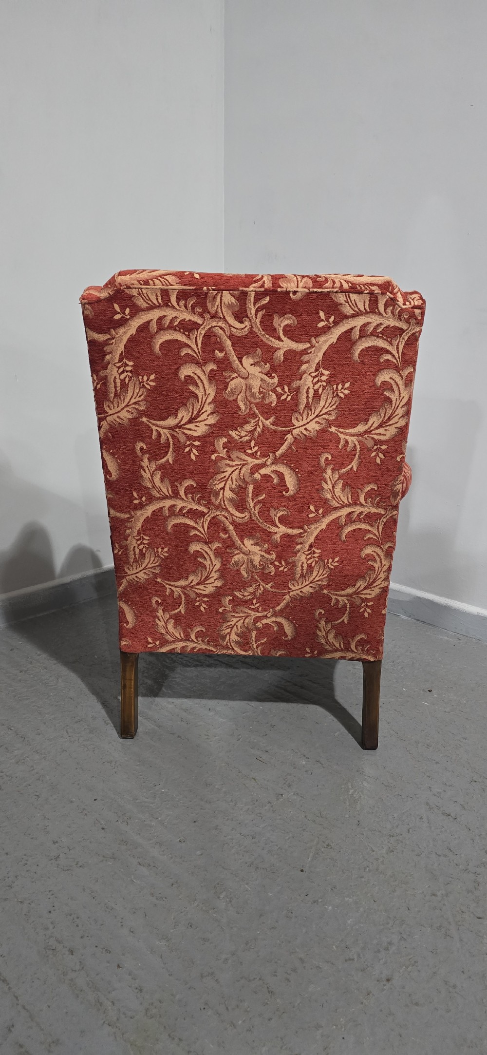A high-backed wing armchair upholstered in red floral damask fabric with carved mahogany cabriole front legs featuring claw and ball feet. View X