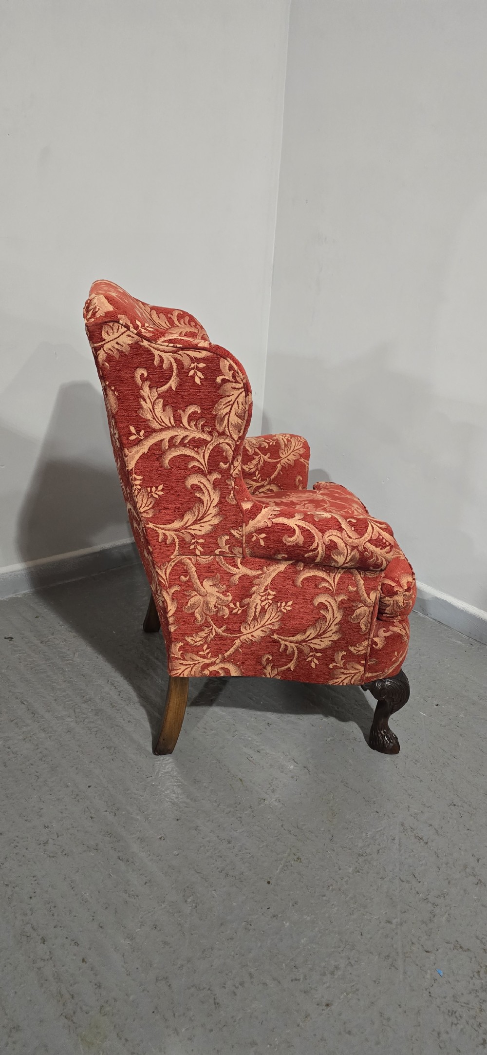 A high-backed wing armchair upholstered in red floral damask fabric with carved mahogany cabriole front legs featuring claw and ball feet. View XI