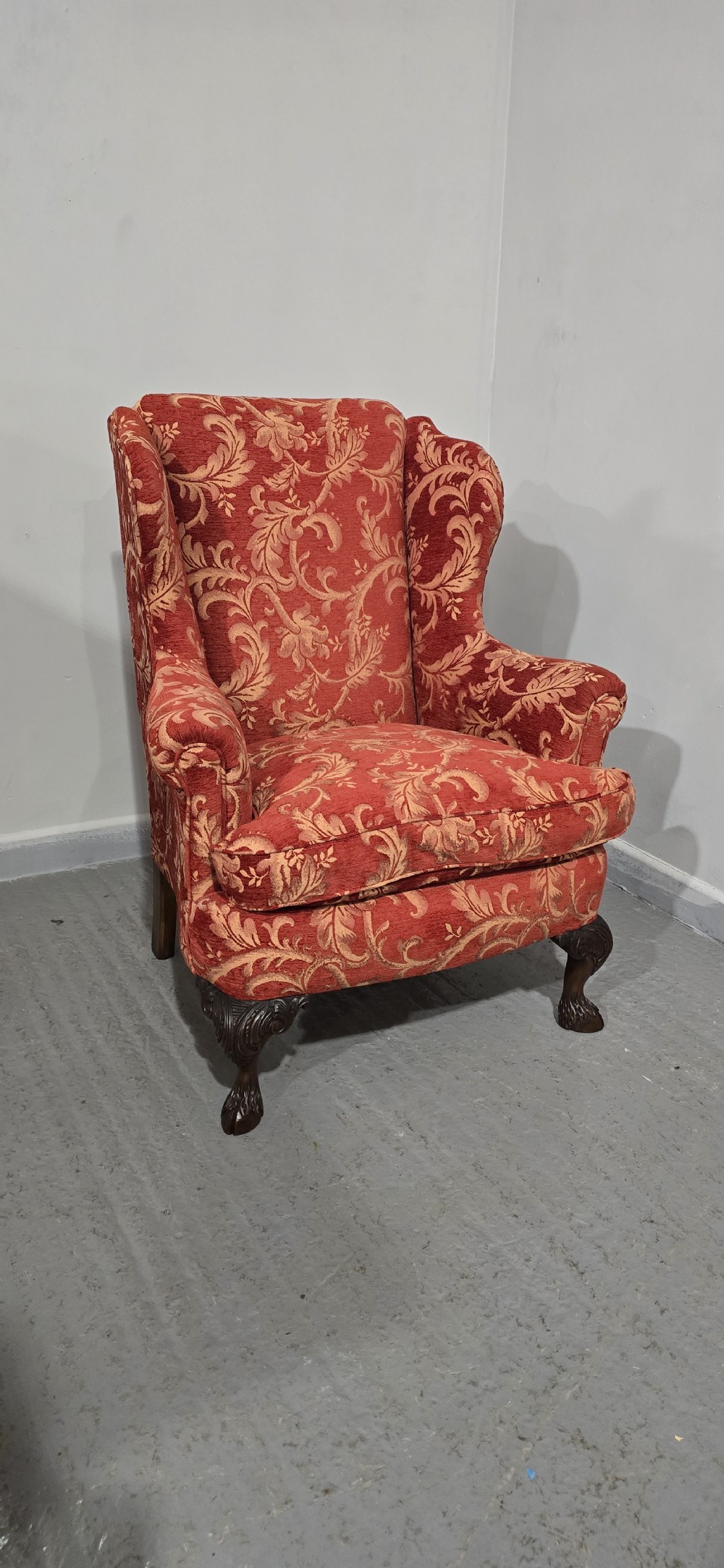 A high-backed wing armchair upholstered in red floral damask fabric with carved mahogany cabriole front legs featuring claw and ball feet. View XII