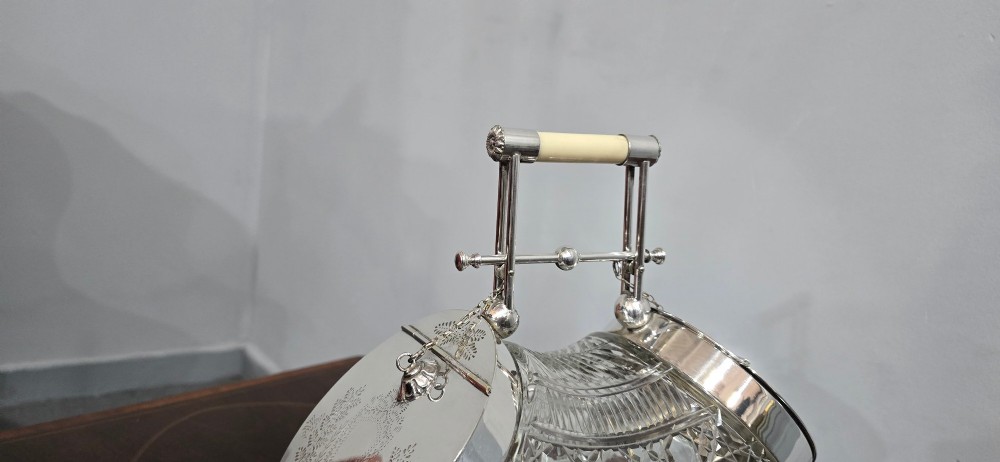 An Edwardian cut glass biscuit barrel featuring a hobnail geometric pattern, silver-plated frame, overhead handle, and pedestal base. View IV