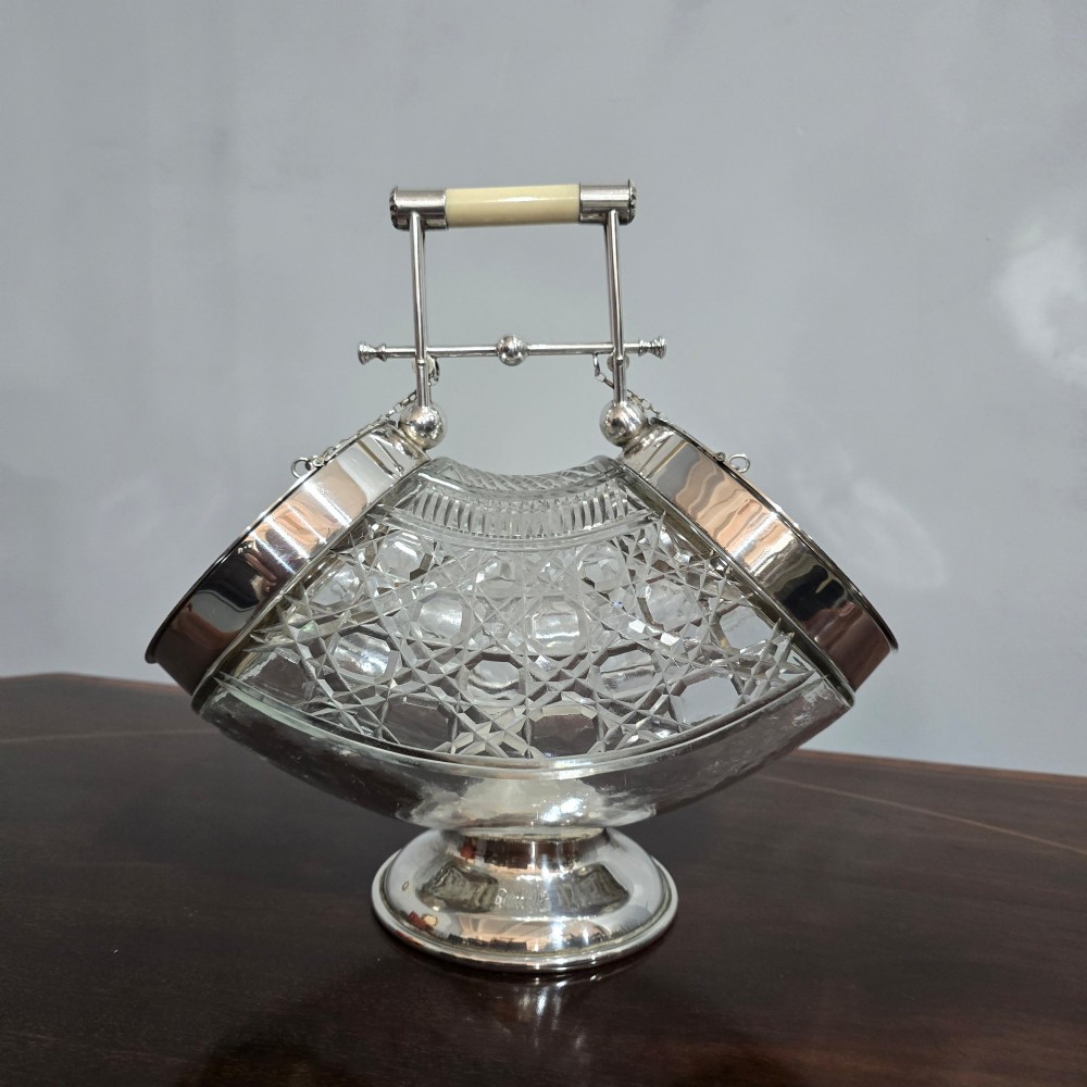 An Edwardian cut glass biscuit barrel featuring a hobnail geometric pattern, silver-plated frame, overhead handle, and pedestal base. View VIII