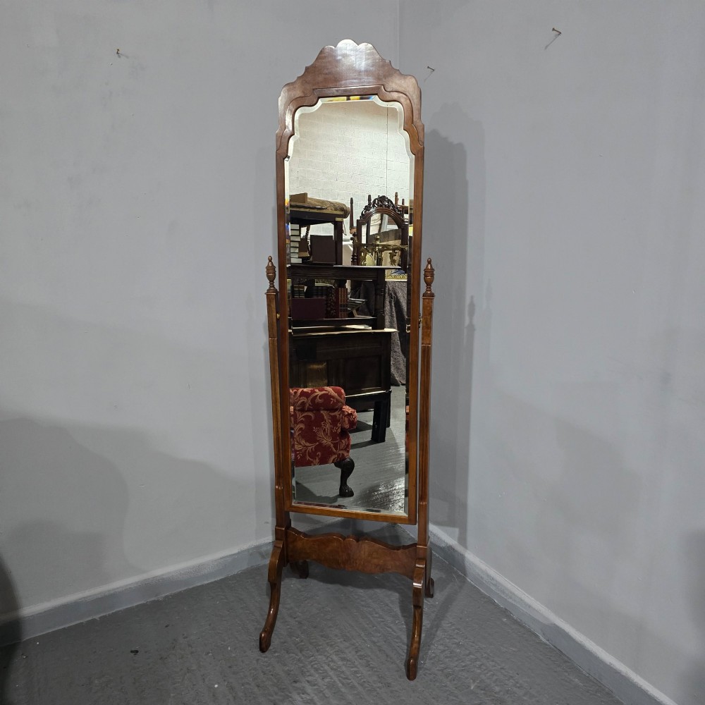 A standing Queen Anne style burr walnut cheval mirror featuring a shaped crest, tilting glass plate, finial-topped uprights, and cabriole legs. View X