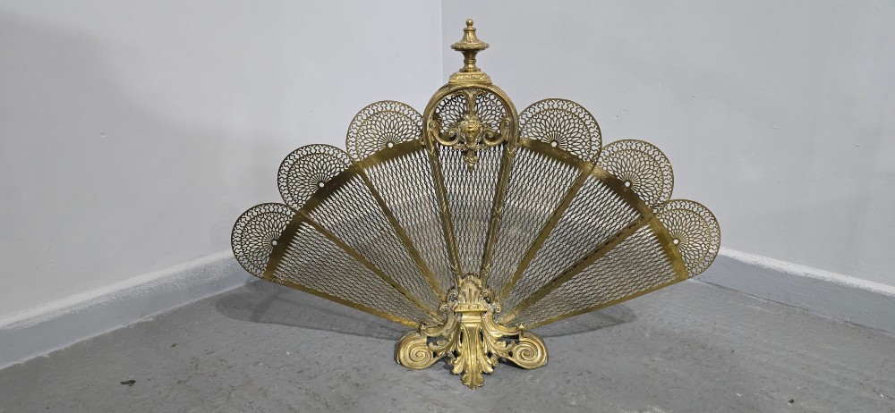 An ornate Victorian brass peacock fire screen featuring pierced filigree fan panels, a finial crest, and a cast scrollwork base. View II