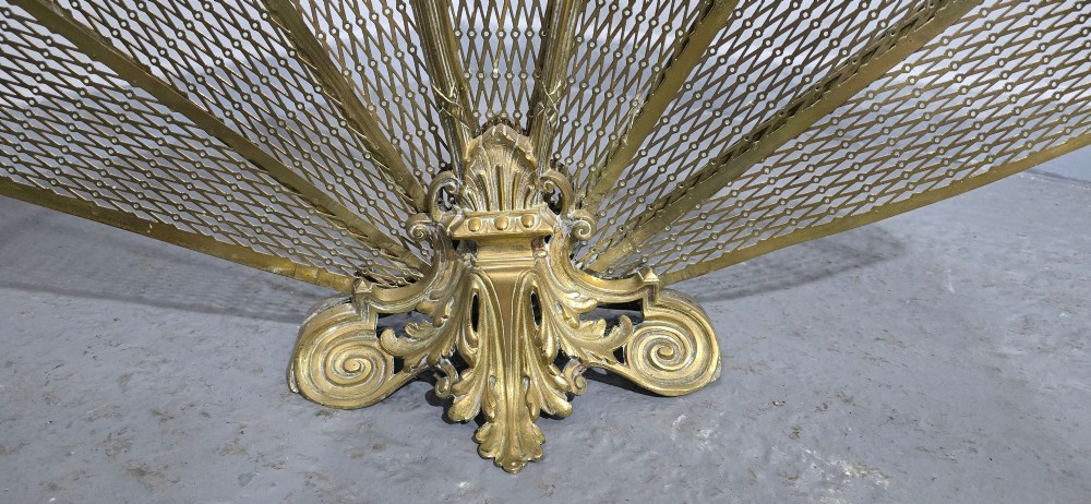 An ornate Victorian brass peacock fire screen featuring pierced filigree fan panels, a finial crest, and a cast scrollwork base. View V