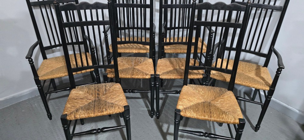 A set of eight Arts and Crafts ebonised wooden dining chairs featuring high spindle backs and hand-woven natural rush seats. View IV