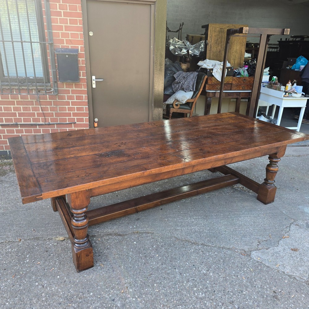 A large solid oak refectory dining table featuring a wide plank top, breadboard ends, turned baluster legs, and a low H-stretcher base. View II