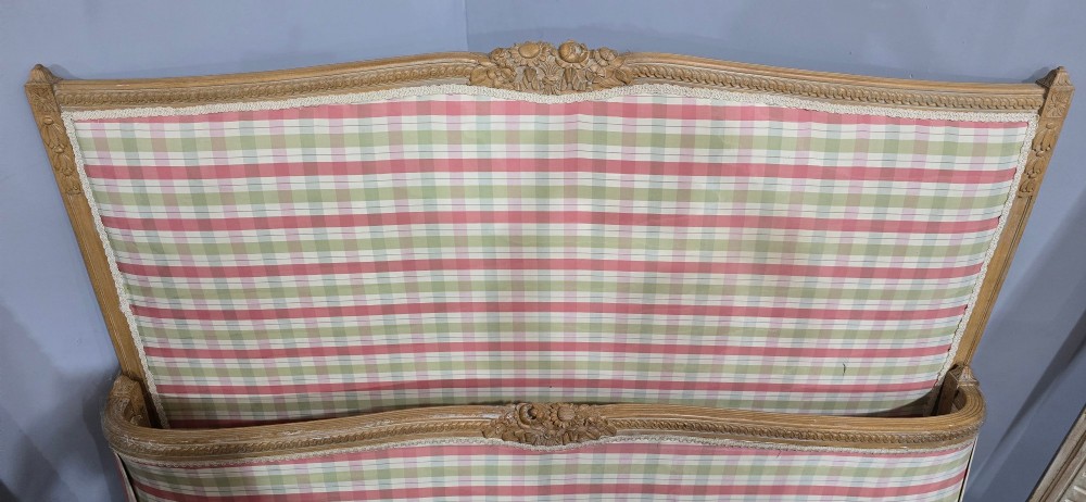 A French double bed frame with a limed wood structure, featuring floral crest carvings, fluted details, and check pattern upholstery. View IX