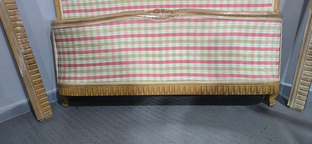 A French double bed frame with a limed wood structure, featuring floral crest carvings, fluted details, and check pattern upholstery. View X