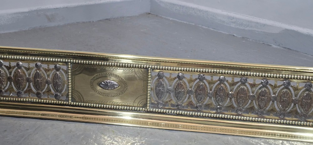 A wide Georgian brass and pierced cut steel fireplace fender with decorative geometric patterns and beaded borders. View V