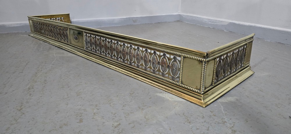 A wide Georgian brass and pierced cut steel fireplace fender with decorative geometric patterns and beaded borders. View X