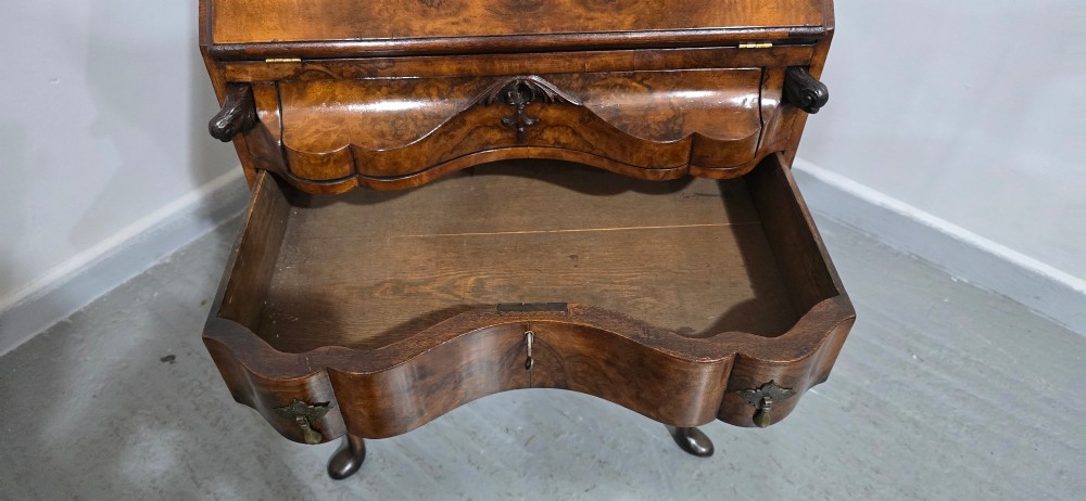 A Queen Anne style burr walnut writing bureau featuring a sloped front lid, shaped drawers with brass drop handles, and tall cabriole legs. View VII