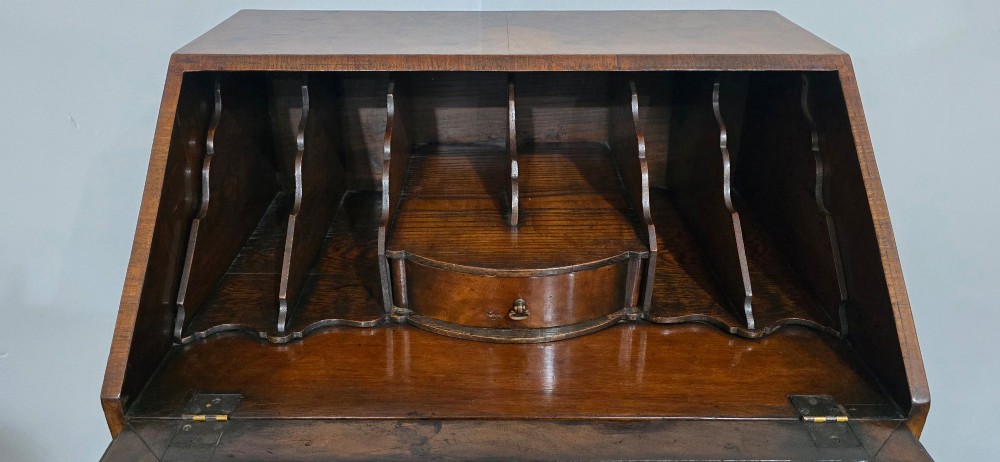 A Queen Anne style burr walnut writing bureau featuring a sloped front lid, shaped drawers with brass drop handles, and tall cabriole legs. View X