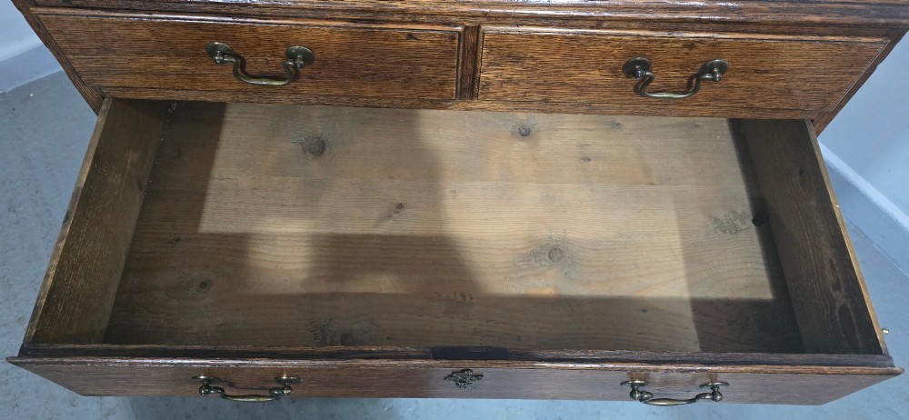 A Georgian oak chest of drawers featuring two short drawers above three long graduated drawers with brass swan-neck handles and bracket feet. View X