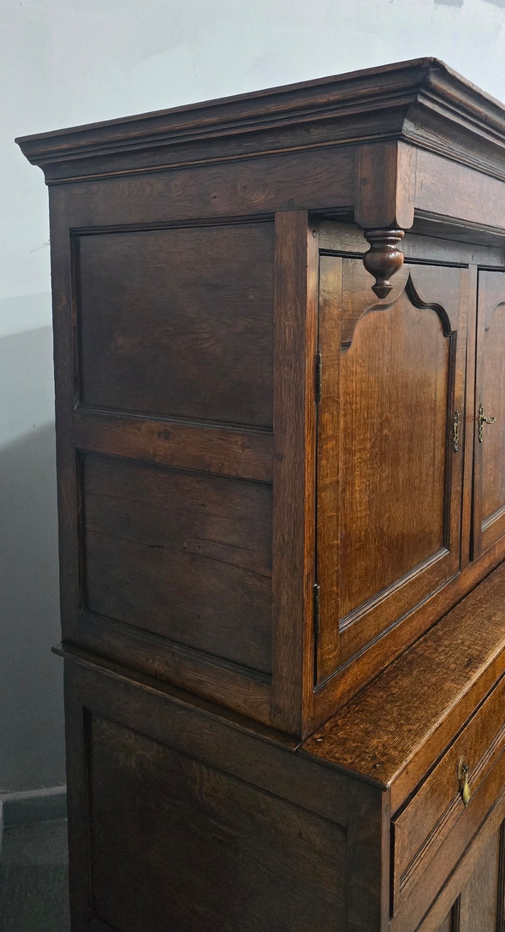 A dark oak Georgian court cupboard featuring an upper cabinet with arched panel doors, two central drawers, and a lower double-door cupboard on bracket feet. View IX