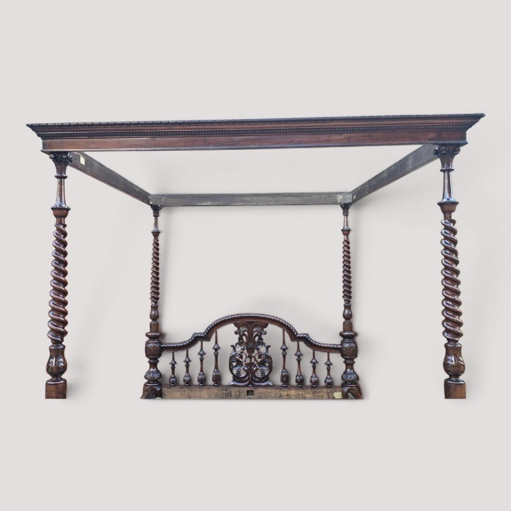 A dark wood four-poster bed frame featuring carved spiral posts, turned spindles, and an arched cresting headboard. View V