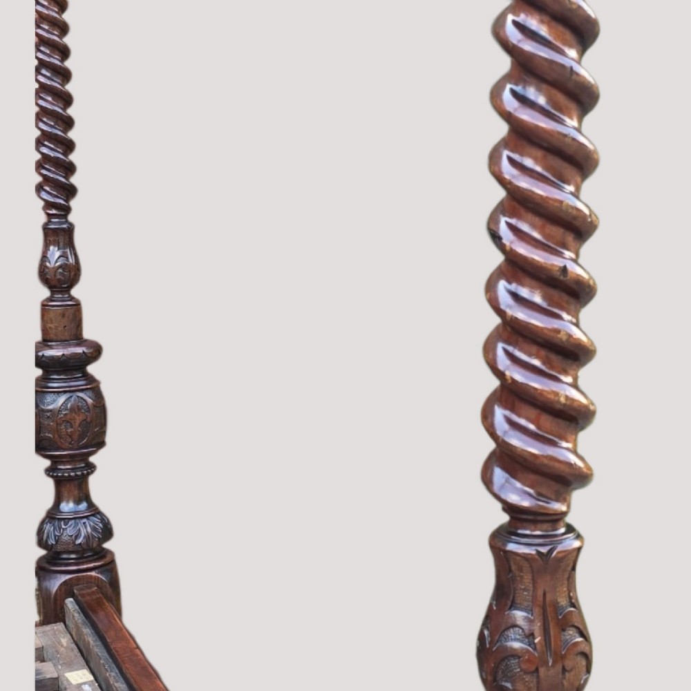 A dark wood four-poster bed frame featuring carved spiral posts, turned spindles, and an arched cresting headboard. View VII