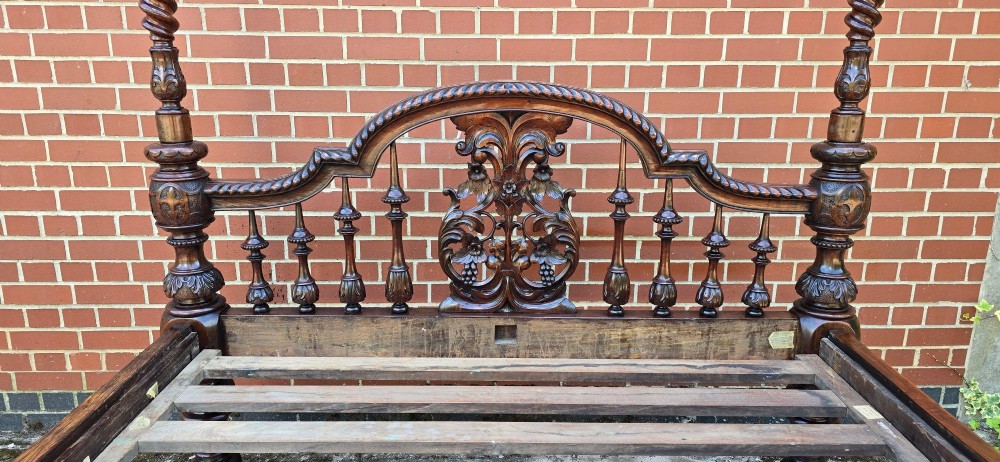 A dark wood four-poster bed frame featuring carved spiral posts, turned spindles, and an arched cresting headboard. View IX