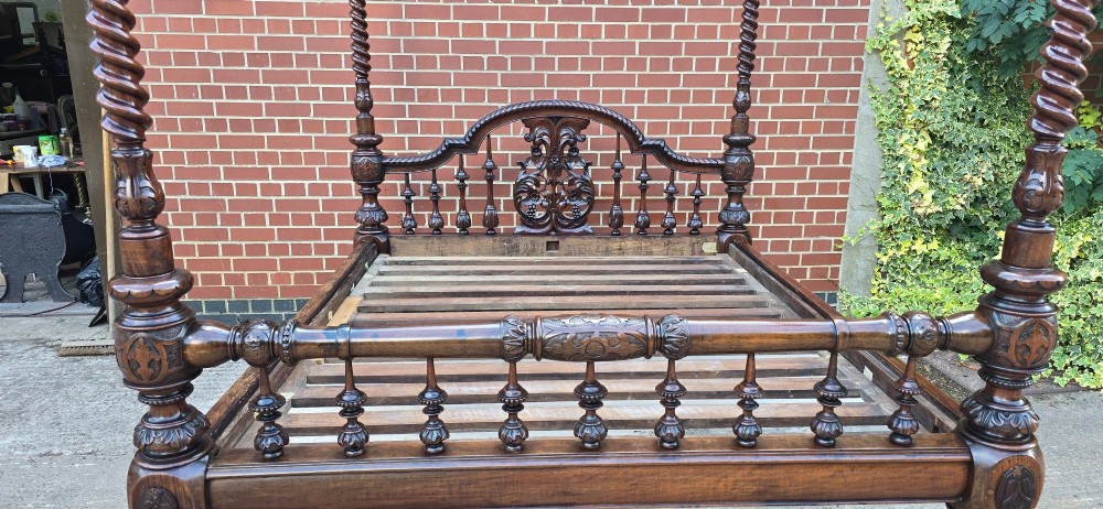 A dark wood four-poster bed frame featuring carved spiral posts, turned spindles, and an arched cresting headboard. View XV