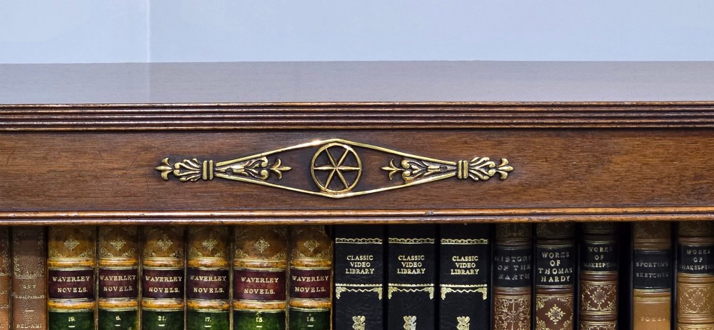 An antique Empire style breakfront low mahogany bookcase featuring three sections of open adjustable shelves filled with books and adorned with gilt bronze mounts and fluted pilasters. View III