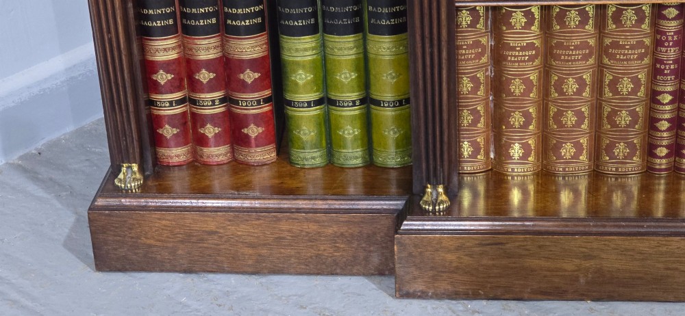 An antique Empire style breakfront low mahogany bookcase featuring three sections of open adjustable shelves filled with books and adorned with gilt bronze mounts and fluted pilasters. View VII