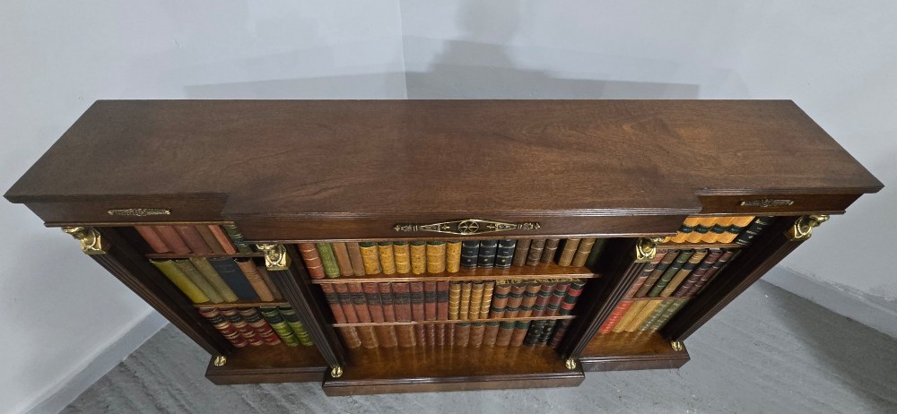 An antique Empire style breakfront low mahogany bookcase featuring three sections of open adjustable shelves filled with books and adorned with gilt bronze mounts and fluted pilasters. View X