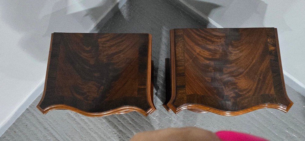 A matching pair of serpentine-fronted mahogany bedside chests, each featuring four drawers with inlay crossbanding and circular brass ring handles. View VII