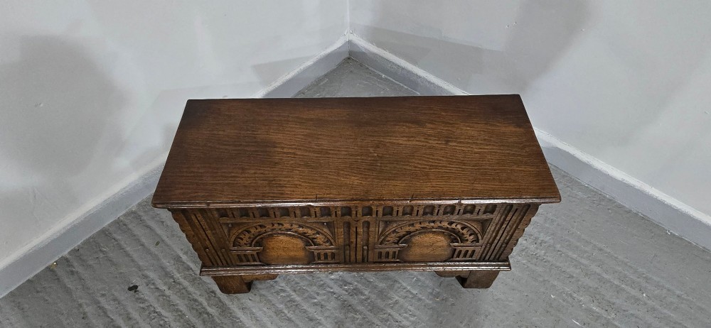 A miniature dark oak coffer featuring carved double arches on the front panel and a hinged rectangular lid. View VI