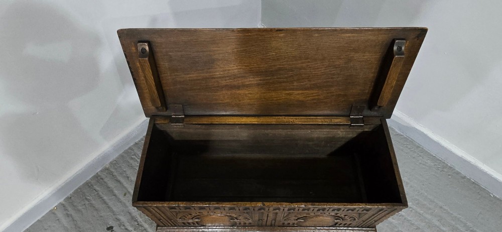 A miniature dark oak coffer featuring carved double arches on the front panel and a hinged rectangular lid. View VII