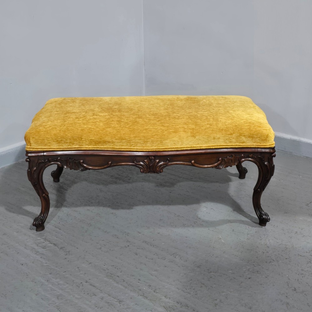 A rectangular Regency period stool featuring a mustard yellow fabric top resting on a dark carved rosewood frame with cabriole legs. View II