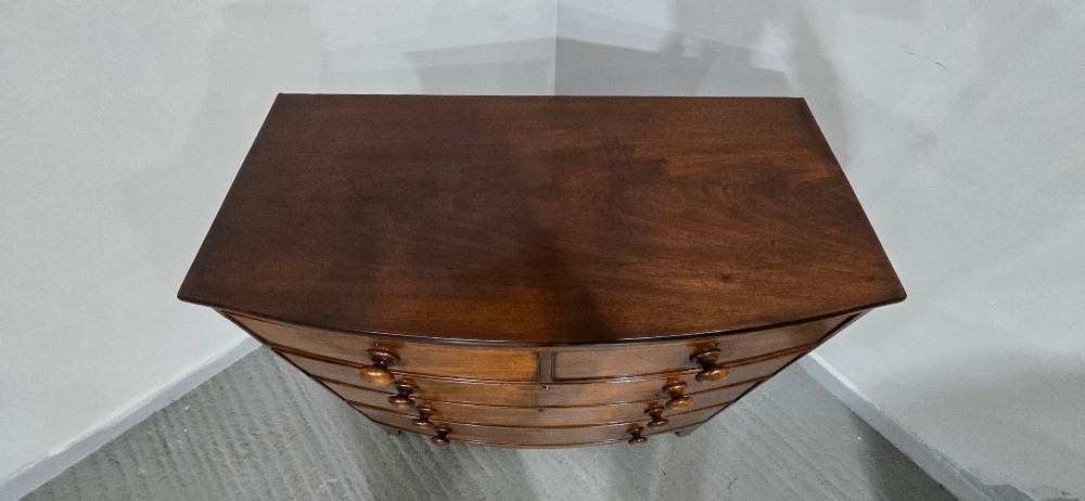 An antique mahogany bow-front chest of drawers featuring two short drawers over three long graduated drawers with turned wooden knobs. View III