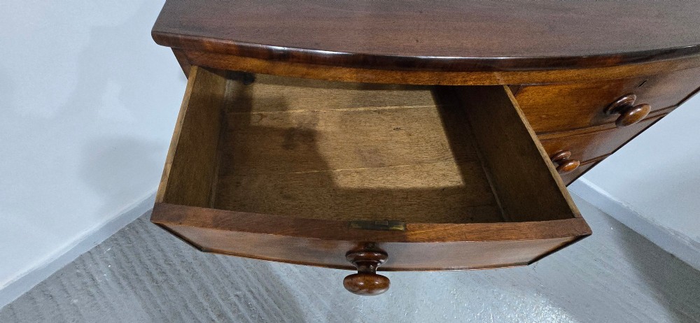An antique mahogany bow-front chest of drawers featuring two short drawers over three long graduated drawers with turned wooden knobs. View VI
