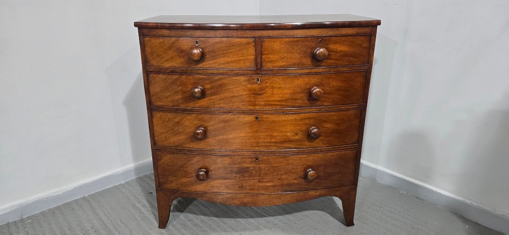 An antique mahogany bow-front chest of drawers featuring two short drawers over three long graduated drawers with turned wooden knobs. View X