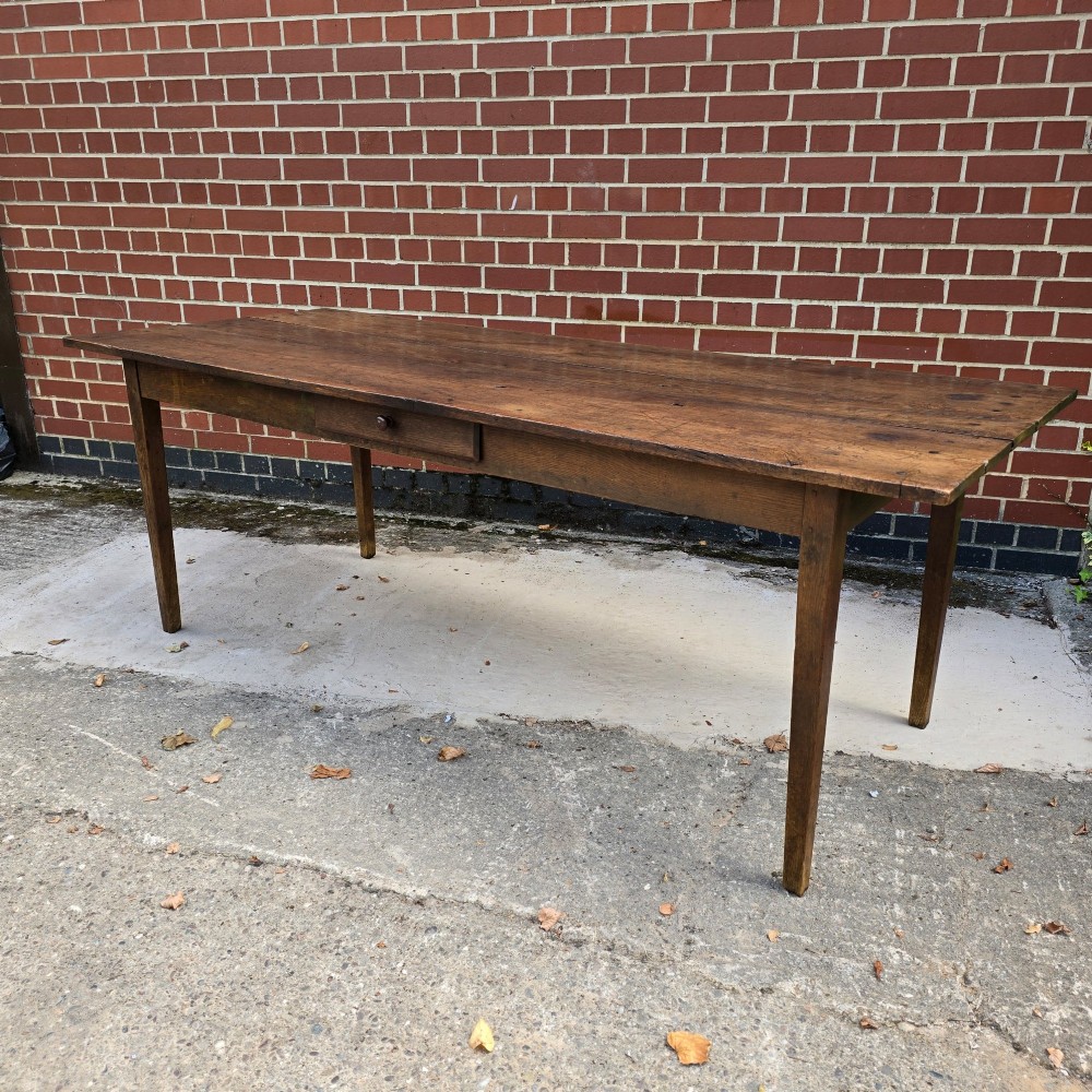 An antique rustic French wooden refectory dining table featuring a three-plank top, single side drawer, and square tapered legs. View II