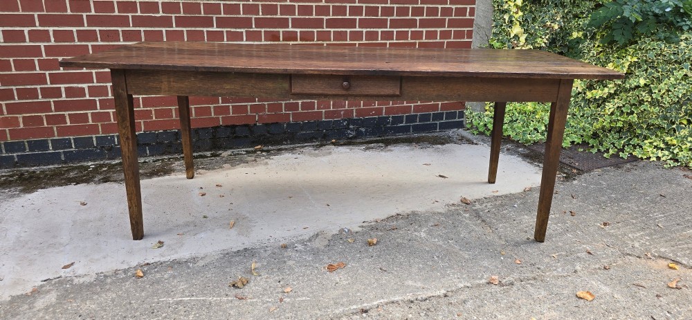 An antique rustic French wooden refectory dining table featuring a three-plank top, single side drawer, and square tapered legs. View IV
