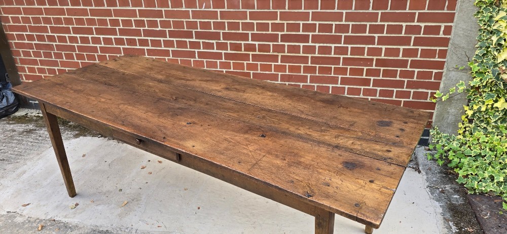 An antique rustic French wooden refectory dining table featuring a three-plank top, single side drawer, and square tapered legs. View VI