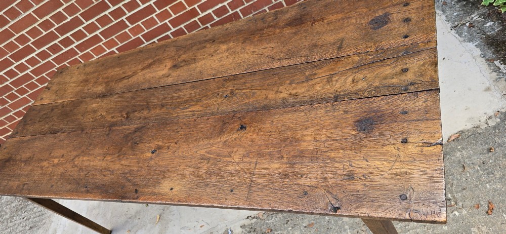 An antique rustic French wooden refectory dining table featuring a three-plank top, single side drawer, and square tapered legs. View VIII