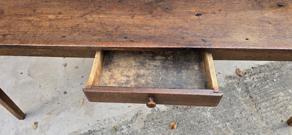 An antique rustic French wooden refectory dining table featuring a three-plank top, single side drawer, and square tapered legs. View XI